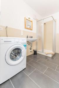 eine Waschmaschine im Bad mit Dusche in der Unterkunft Modernes Apartment mit privatem Stellplatz wenige Minuten von der Innenstadt & Mosel in Koblenz