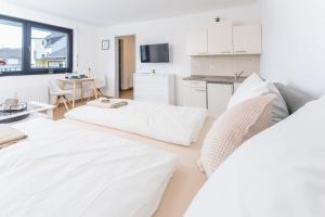 Sala de estar blanca con 2 camas y mesa en Modernes Apartment mit privatem Stellplatz wenige Minuten von der Innenstadt & Mosel, en Coblenza