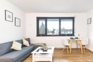ein Wohnzimmer mit einem Sofa und einem Tisch in der Unterkunft Modernes Apartment mit privatem Stellplatz wenige Minuten von der Innenstadt & Mosel in Koblenz