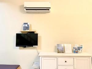 a room with a tv and a air conditioner on a wall at Loju sunrise inn in Xiaoliuqiu