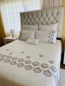 a bed with a white bedspread with a flower pattern at Third Haven in Swakopmund