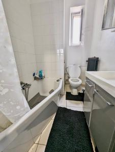 a white bathroom with a tub and a toilet at Excellent T2 - 5min Gare & HyperCentre in Grenoble