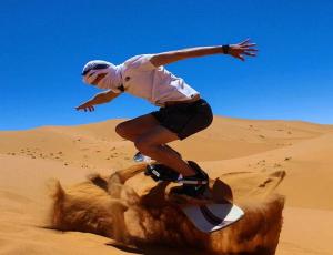 a man riding a snowboard in the desert at Horaz luxury camp in Merzouga