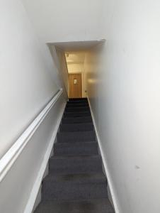eine Treppe, die zu einem Zimmer mit weißen Wänden führt in der Unterkunft Stepney Green Self Contained Studio in London