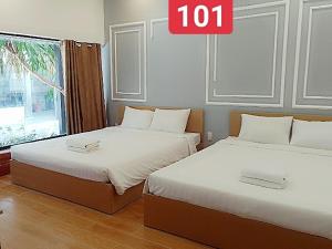 two beds in a room with a sign that reads at VND Vũng Tàu Hotel & Villa in Vung Tau