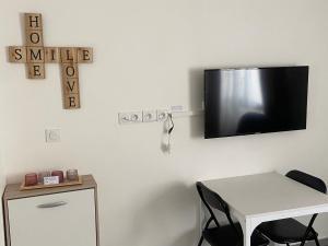 um quarto com uma mesa e uma televisão na parede em Jolie perle em Saint-Priest