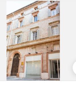 um grande edifício de tijolos com uma porta e janelas em Cozy room in Palazzo Magnalbò em Macerata