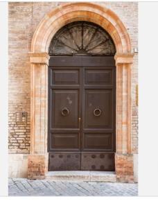 a large black door in a brick building at Cozy room in Palazzo Magnalbò in Macerata