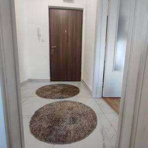 três tapetes castanhos no chão em frente a uma porta em Apartman Ena em Bileća