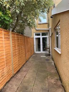 a wooden fence next to a building with a sidewalk at Central 2 bed flat with off street-parking in Bristol