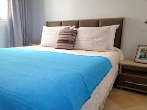 Elle comprend un grand lit avec une couverture bleue et des oreillers blancs. dans l'établissement Maison LIANE familiale au calme, à Hammamet