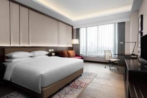 a bedroom with a large white bed and a desk at Courtyard by Marriott Suzhou Mudu in Suzhou