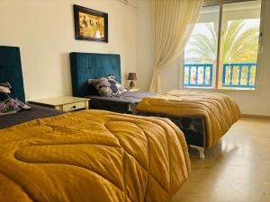 een slaapkamer met 2 bedden en een groot raam bij Marina Retreat in Hammamet