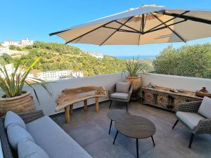 a patio with a couch and a table and an umbrella at Villa Lomy Casares in Casares