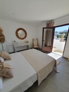 a white bedroom with a large bed and a mirror at Villa Lomy Casares in Casares