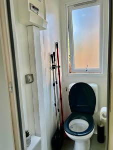La salle de bains est pourvue de toilettes avec un siège noir et une fenêtre. dans l'établissement Camping MAYOTTE TOHAPI 5 étoiles, à Biscarrosse