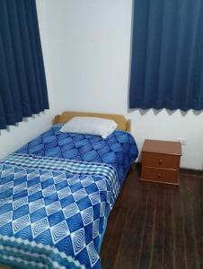 1 dormitorio pequeño con 1 cama y cortinas azules en Black Sheep Hostel Cusco, en Cusco
