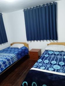 2 camas en una habitación con cortinas azules en Black Sheep Hostel Cusco, en Cusco