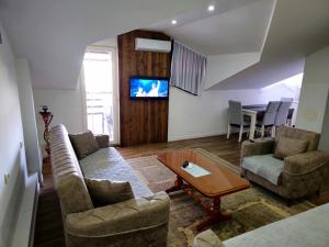 a living room with two couches and a tv at SA Apartment in Gjilan