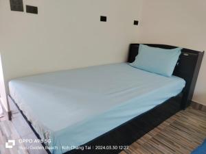 łóżko w pokoju z niebieską poduszką w obiekcie Yuyu Golden Beach w mieście Ko Chang