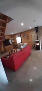a red couch in a living room with a fireplace at Gite châlet nature haute vosges in Anould