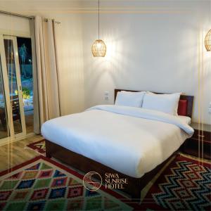 Siwa Sunrise Hotel في سيوة: غرفة نوم بسرير كبير مع شراشف بيضاء