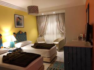 a bedroom with two beds and a desk and a room at ALMADIAFAH APARTMENT - المضيفة للوحدات الفندقيه in Mansoura