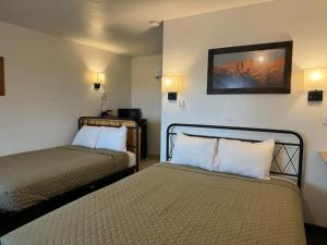 Eastern Sierra Motor Lodge في إندبينديس: غرفه فندقيه سريرين في غرفه