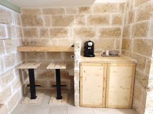 a table and two stools in a room with a stone wall at Minuetto 54 in Ostuni