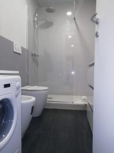 uma casa de banho branca com um chuveiro e uma máquina de lavar roupa em VARAZZE SUITE IDROMASSAGGIO E SAUNA em Varazze
