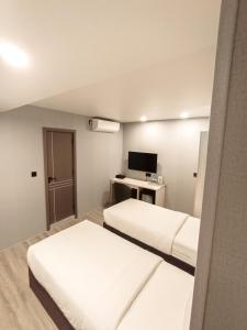 a hotel room with two beds and a television at Starry Beach Inn in Hulhumale