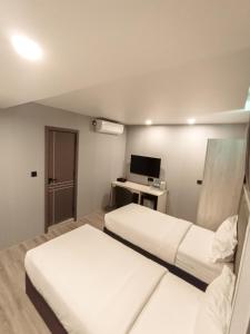 a hotel room with two beds and a television at Starry Beach Inn in Hulhumale