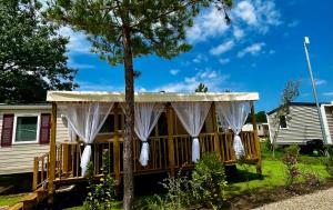 a screened in porch with white curtains and a tree at Au Ferret plage,piscines à 2 pas en famille by Vayny in Lège-Cap-Ferret