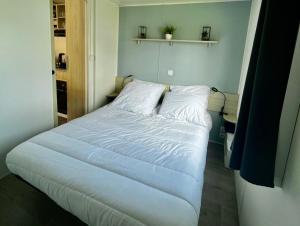 a bedroom with a bed with white sheets at Au Ferret plage,piscines à 2 pas en famille by Vayny in Lège-Cap-Ferret