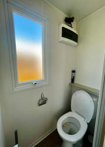 a bathroom with a toilet and a window at Au Ferret plage,piscines à 2 pas en famille by Vayny in Lège-Cap-Ferret +15 photos