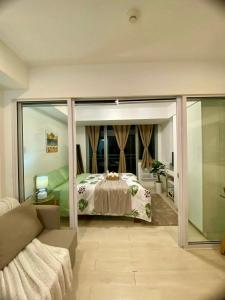 1 dormitorio con 1 cama y sala de estar con sofá en Bellescapes - Azure Resort (1 BR with Balcony), en Manila