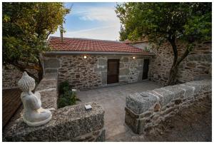 a stone house with a statue in front of it at Alojamento Estrela Cottage in Torrozelo +5 photos