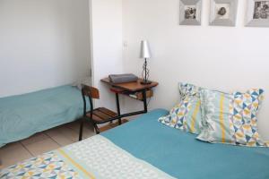 ein Schlafzimmer mit einem Bett und einem Tisch mit einem Stuhl in der Unterkunft Glycine in Le Petit-Quevilly