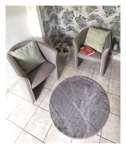 een woonkamer met 2 stoelen en een tapijt bij Studio 11 - Longère Bruyères - Morbihan in Sulniac