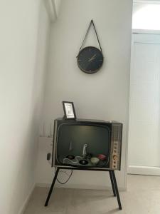 einen TV auf einem Stand mit einer Uhr an der Wand in der Unterkunft Rétro in Carovigno