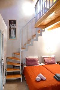 a bedroom with a bed with an orange blanket and stairs at Kalokenti Studios in Aegina Town