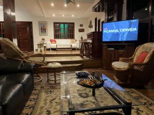 a living room with a couch and a tv at Mansão Itaúna Espetacular in Saquarema