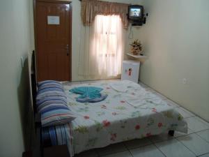 Cama pequeña en habitación con TV en Pousada da Mari, en Gramado