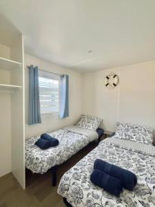 2 camas en una habitación con almohadas azules en Mobil Home Abricotiers 1 en Valras-Plage