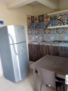 eine Küche mit einem Kühlschrank aus Edelstahl und einem Tisch in der Unterkunft Casa Marcella in Playa Dormida