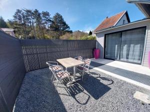 a table and chairs on a patio with a fence at le chalet d Alex in Étretat