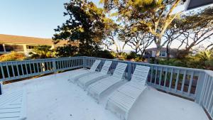 three white chairs sitting on top of a balcony at OCEAN RETREAT home in Jekyll Island