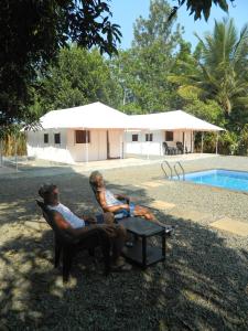 un hombre y un niño sentados en una silla junto a una piscina en Torch Ginger Homestay en Sultans Battery