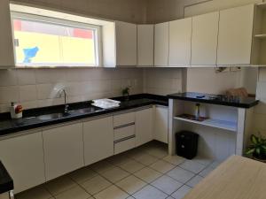 a kitchen with white cabinets and a sink and a window at Kite and Dreaming House in Cumbuco