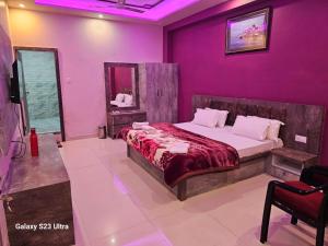 um quarto com uma cama e uma parede roxa em Kashi Inn Raj Ghat Varanasi BY GRG em Varanasi